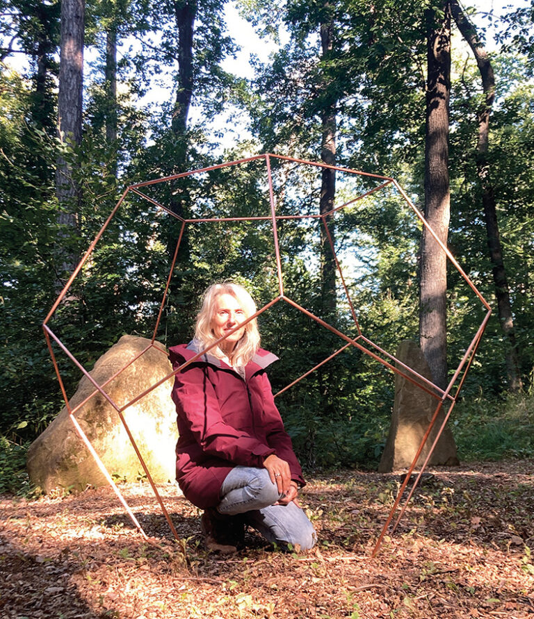 Eine Frau mit blonden Haaren kniet im Wald