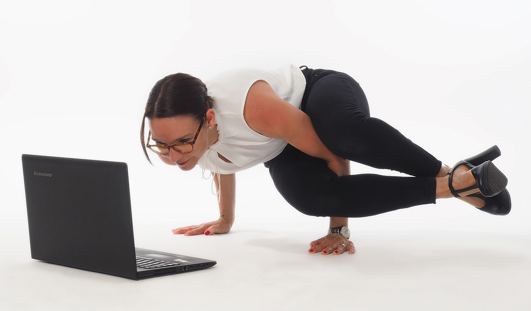 Frau in Businesskleidung in einer Yogahaltung vorm Computer