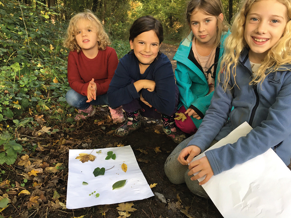 Kinder sitzen in der Hocke im Wald or einem Papier mit bunten Laubblättern drauf