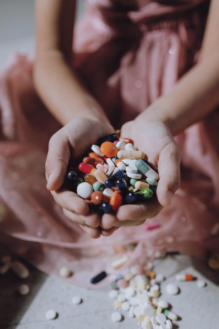 Zwei volle Hände mit bunten Tabletten